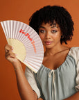 Curly haired woman holding pink Hot Flush Summer Fan too her face
