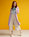 Red haired woman wears lilac cardigan and beige linen culottes