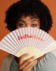Curly haired woman holding pink Hot Flush Summer Fan over her face