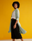 Curly haired woman spinning in mint cardigan