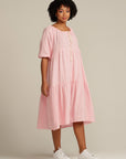 brown woman wearing a pink linen knee length dress
