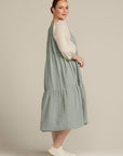 side view of sage linen dress, woman is looking at camera