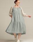 woman smiling looking away wearing a sage green and natural linen dress