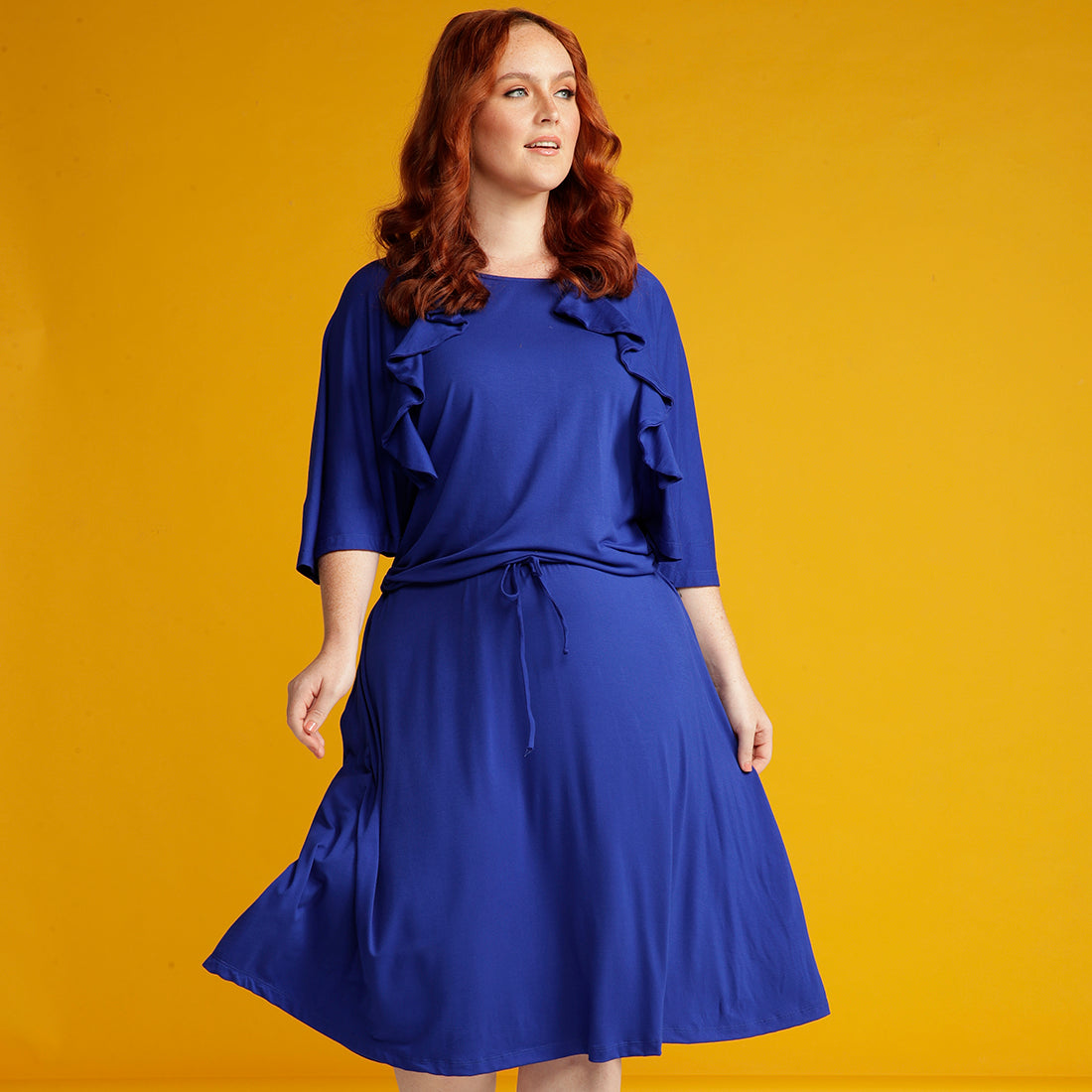 Red haired woman in blue dress with ruffle detail