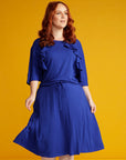 Red haired woman in blue dress with ruffle detail