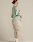 Side view plus size woman in mint green top with ruffle detail
