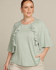 Close up plus size woman in mint green top with ruffle detail