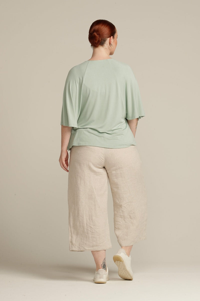 Back view plus size woman in sage green top with ruffle detail
