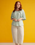 Plus sized woman in adaptive mint green top with ruffle detail