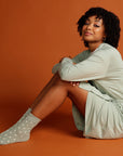 woman sitting down in mint cardigan with mint spotty socks