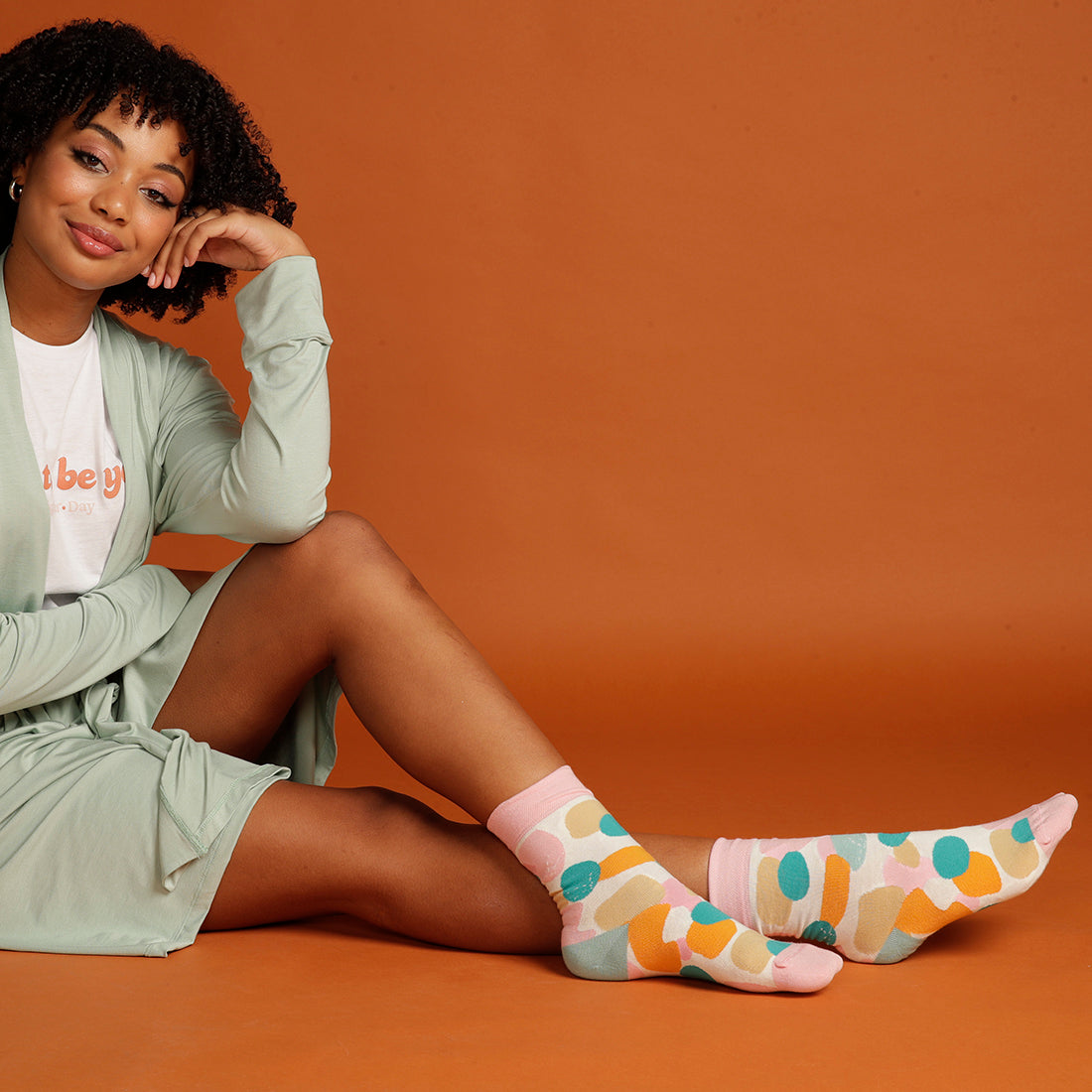 woman sitting down in mint cardigan with colourful spotty socks