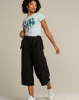 Walking curly haired woman wearing black linen culottes