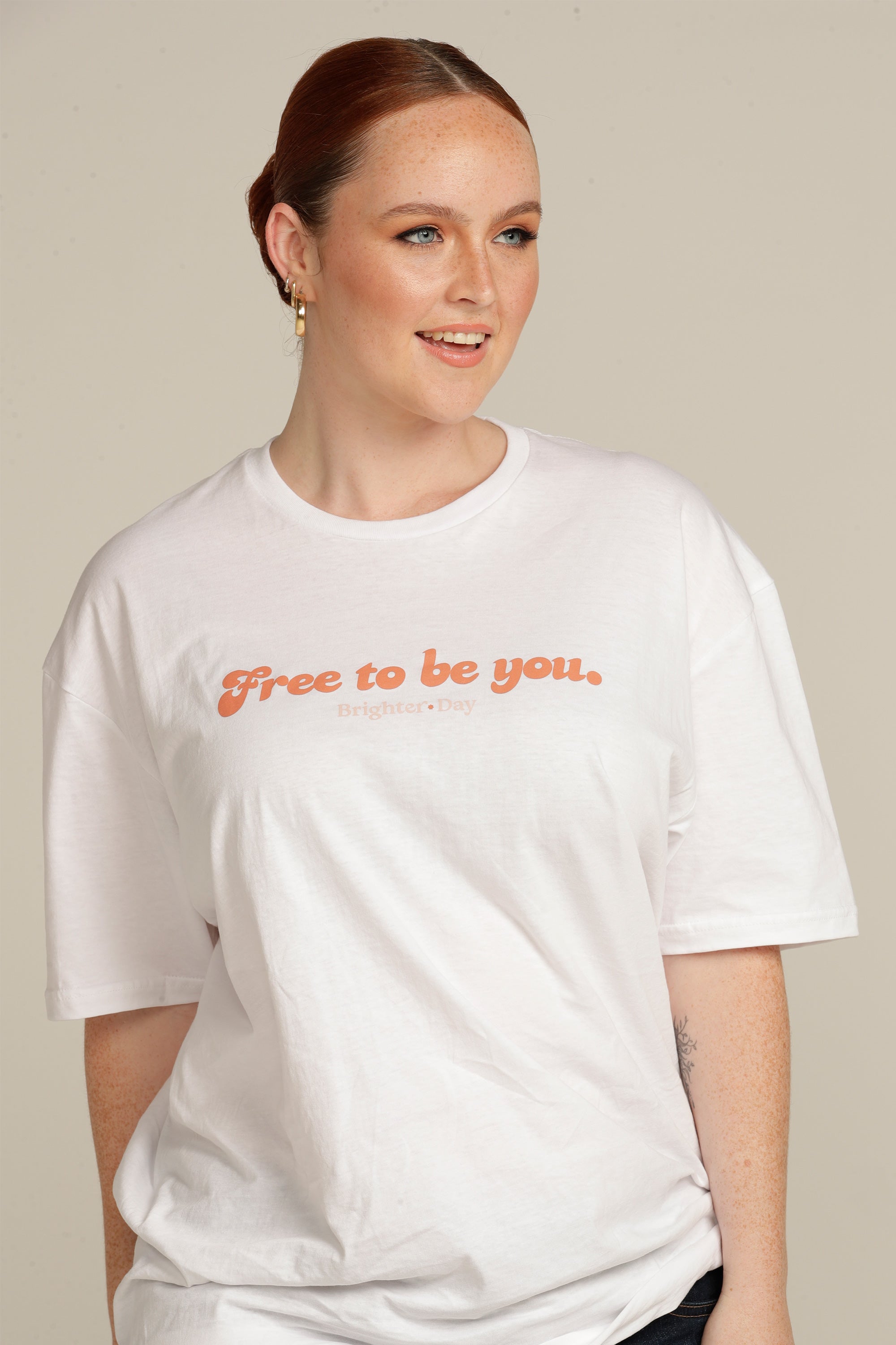 Red Haired woman wears white Free To Be You tee