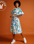 orange background, brown woman wearing a colourful dress with ruffles