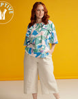 woman wearing printed adaptive top with ruffle and zip detail, an adaptive logo is in the top left corner