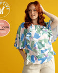 woman wearing an adaptive shirt with a colourful print. she has red hair and looking to the side. Adaptive icon and She-com finalist icon appears on the left