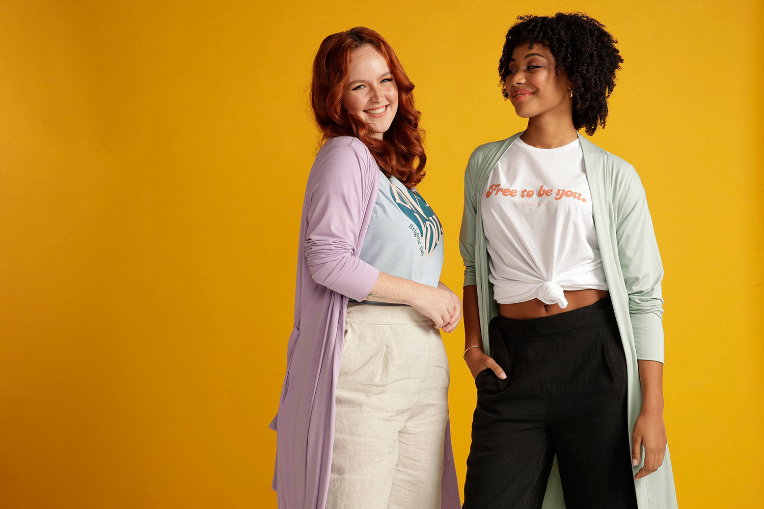 two models wearing linen pants, tee shirts and long bamboo cardigans. one is smiling at the camera the other is looking at the model