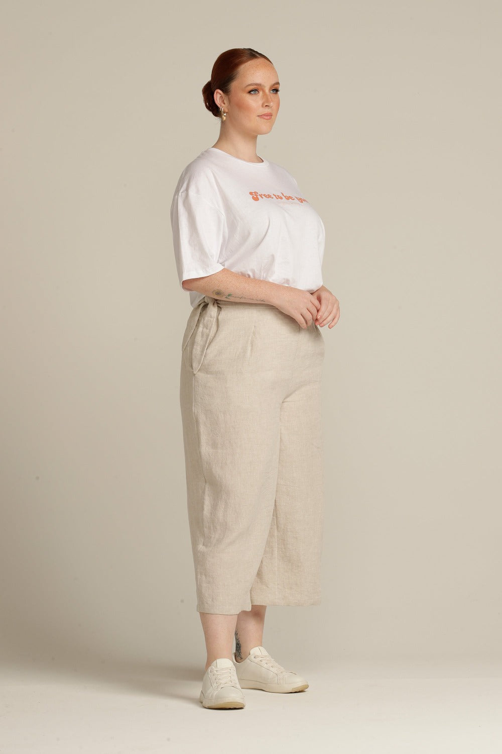 side view of a plus sized woman wearing beige linen culottes