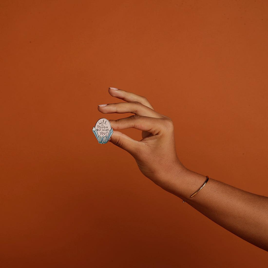Woman holding Life is Tough But So Are You enamel pin