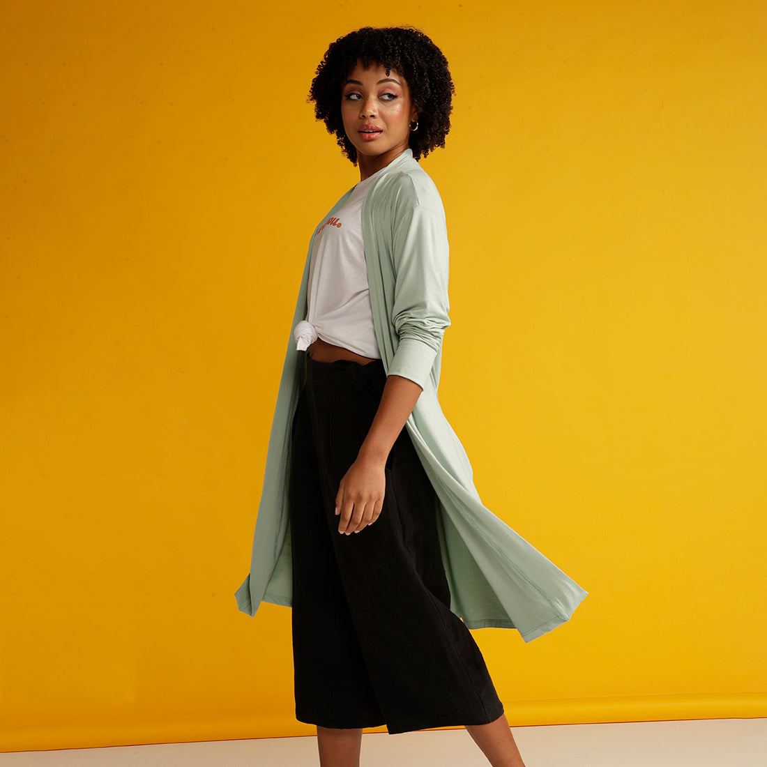 Curly haired woman spinning in mint cardigan