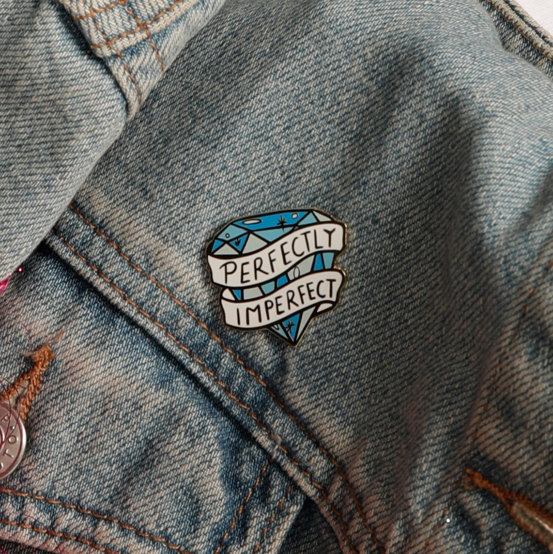 Close up Perfectly Imperfect enamel pin on denim jacket