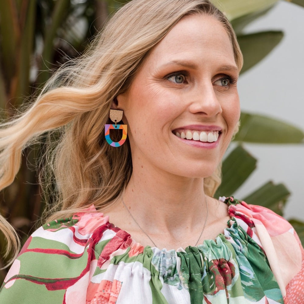 woman wearing green top and colourful rainbow earrings