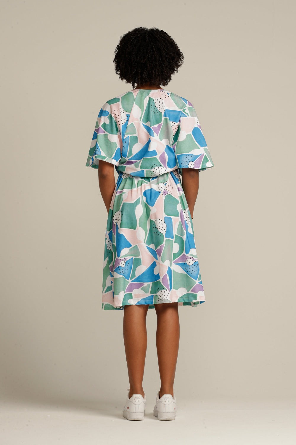 woman wearing a printed knee length ruffle dress facing the back