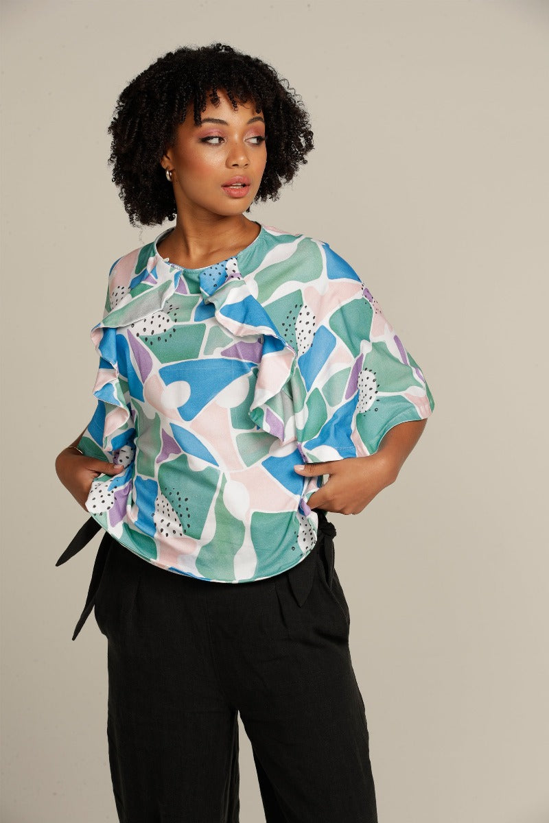 Close up curly haired woman in printed adaptive clothes , top with ruffle detail