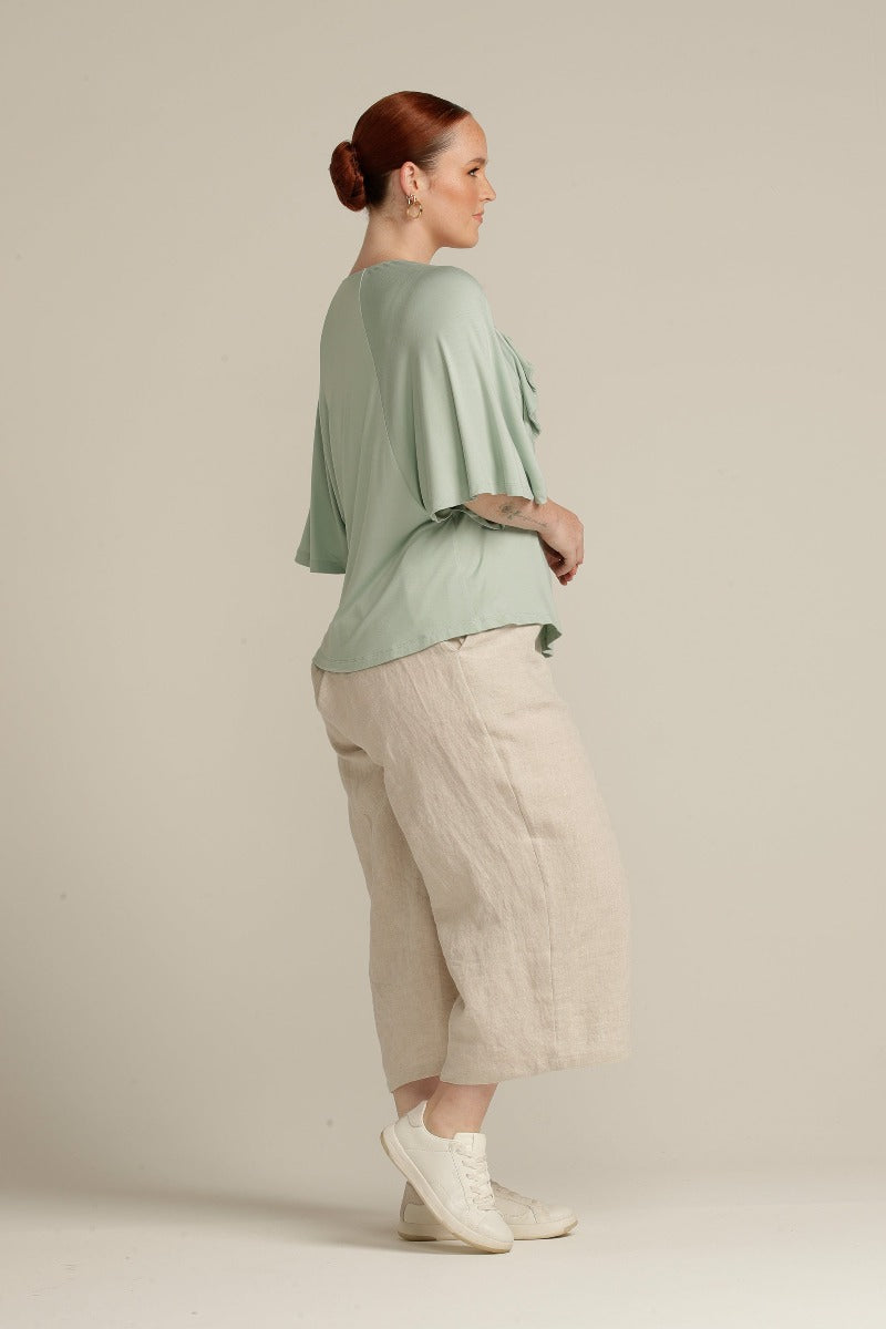 Side view plus size woman in mint green top with ruffle detail
