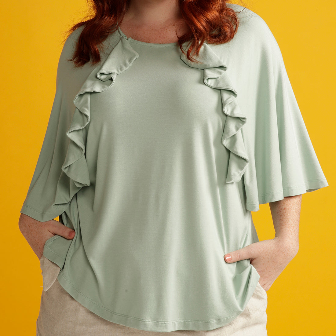 Close up plus sized woman in mint green adaptive top with ruffle detail