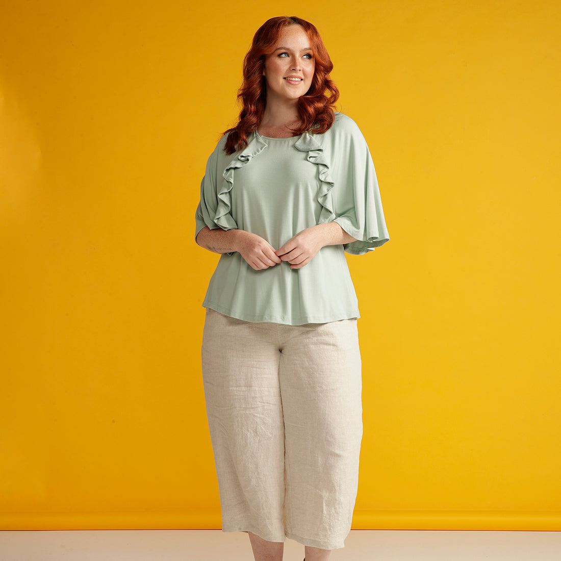 Plus sized woman in adaptive mint green top with ruffle detail