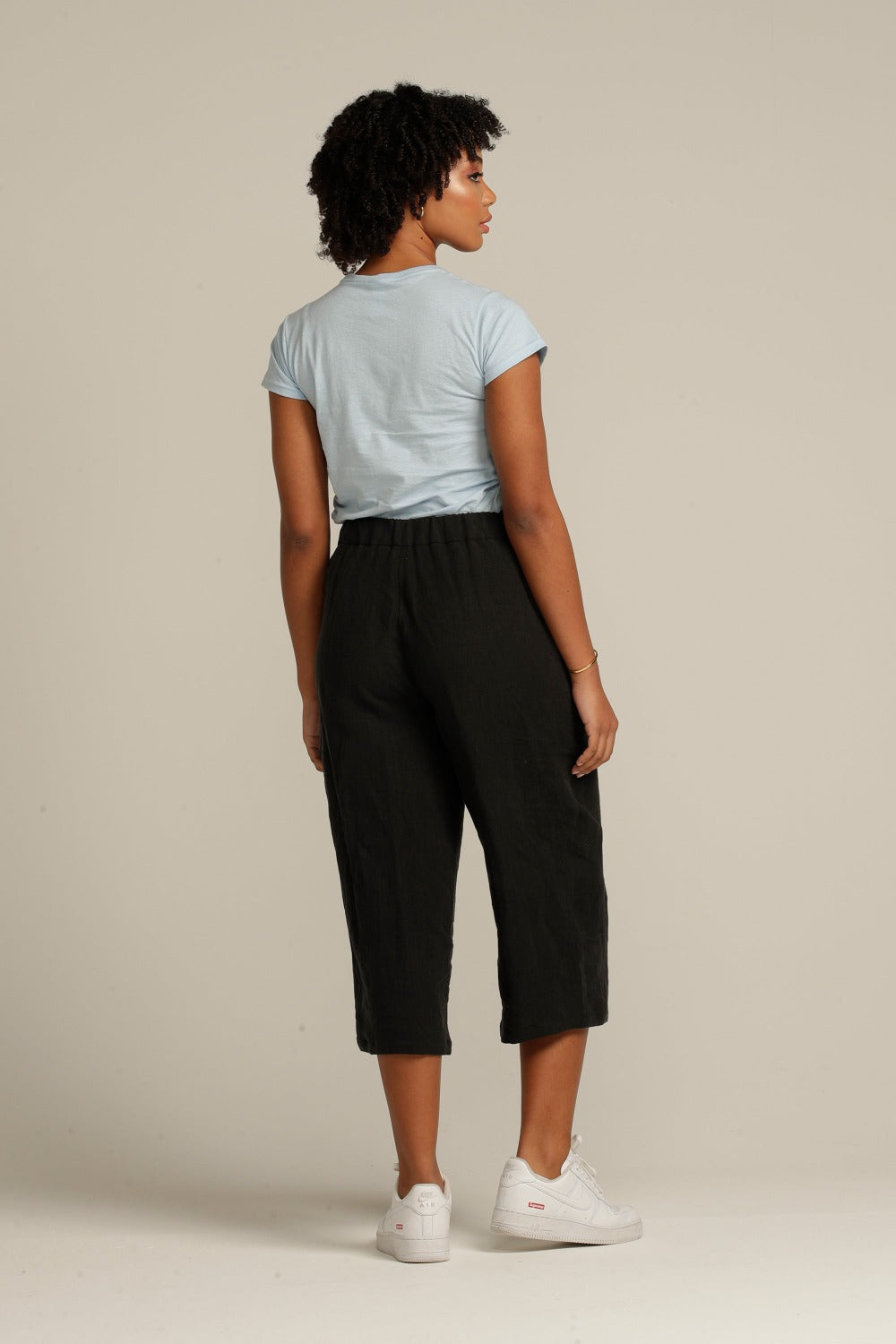 Back view of a curly haired woman wearing black linen culottes