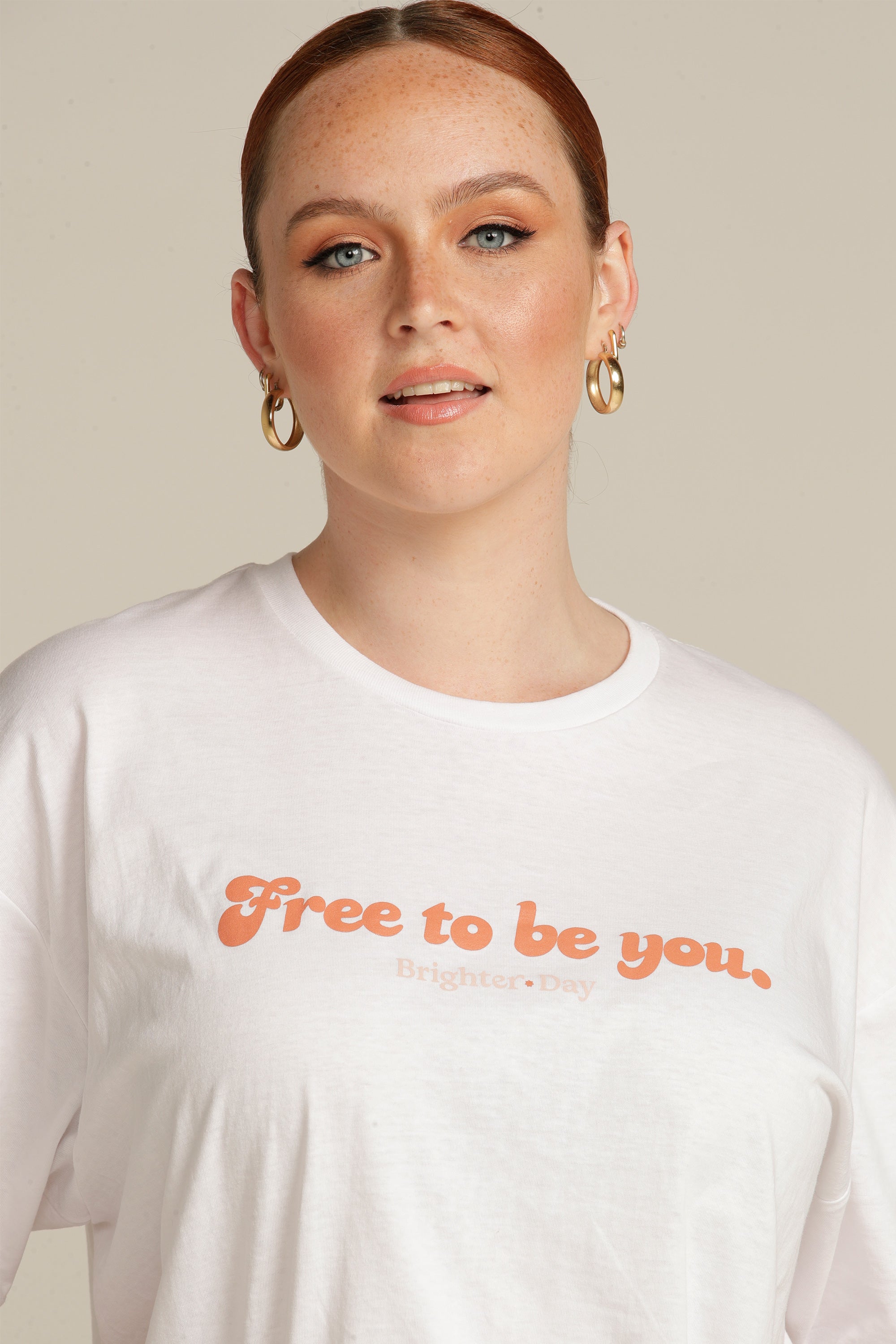 Close up of a red haired woman wearing a white Free To Be You tee