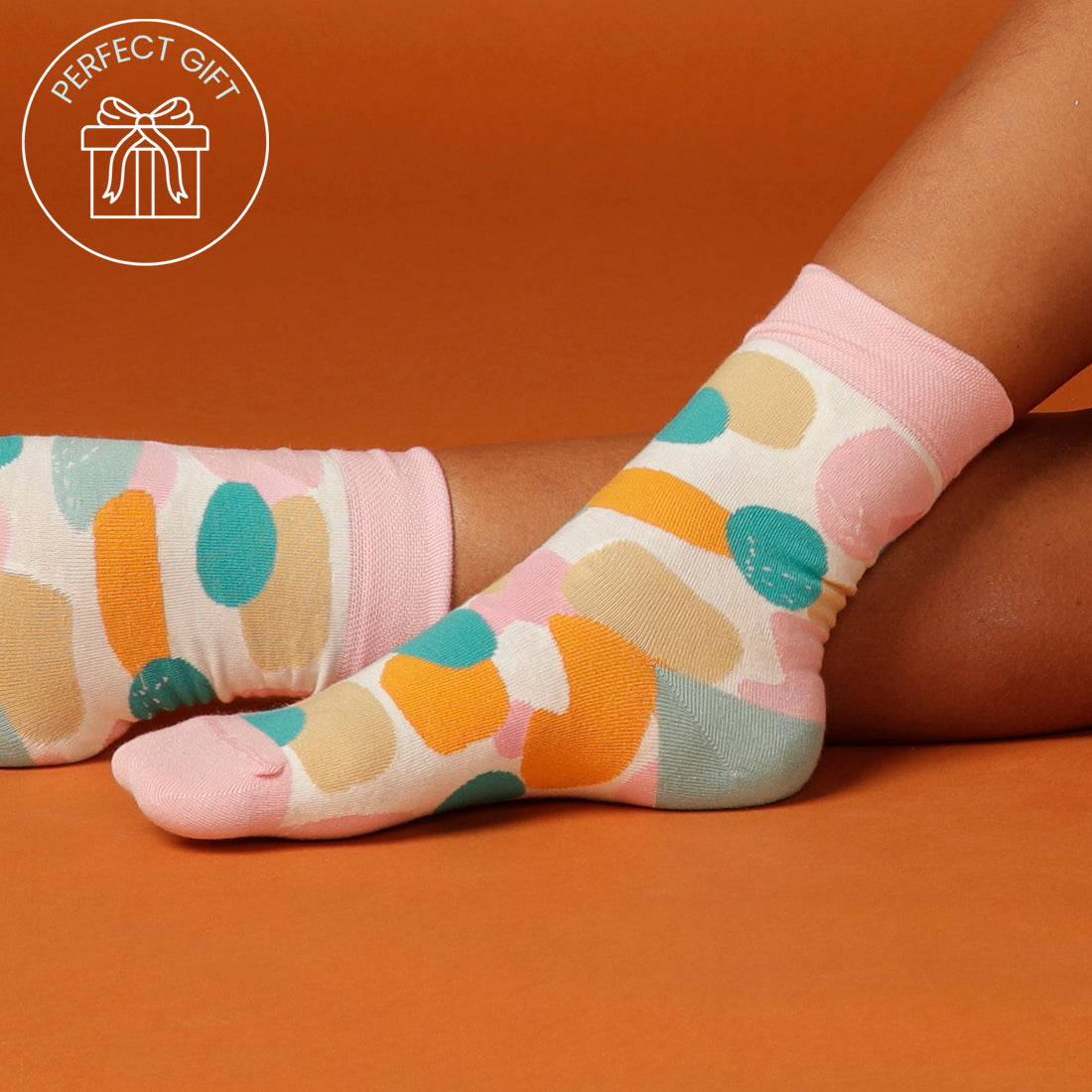 close up of socks with colourful splotches with an orange background